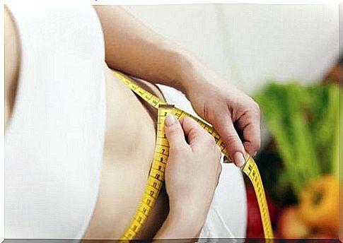 Woman measuring her belly with a measuring tape