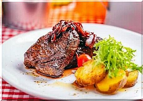 Beef topped with onions along with baked potatoes.