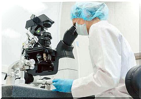 A laboratory technician looking into a microscope.