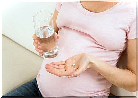 A pregnant woman with a pill and a glass of water