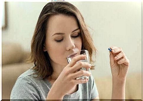 Woman drinks water and takes a pill