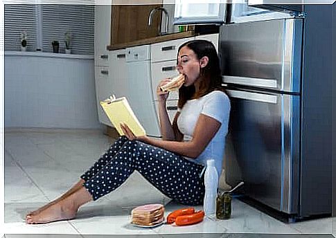 Woman sitting in front of the fridge and eating